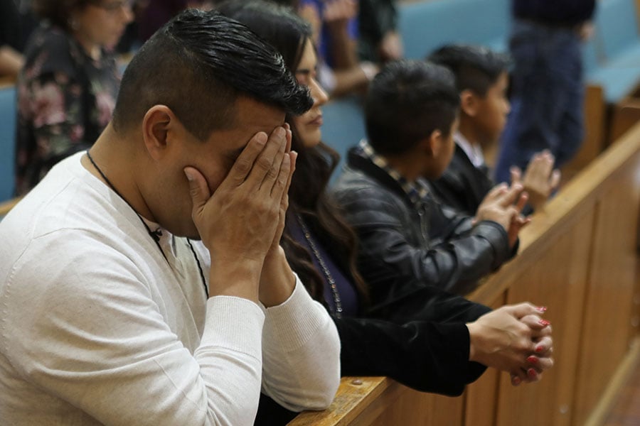 un padre se cubre los ojos durante la misa